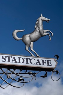 Hanging sign of 'Stadtcafe' against a blue sky