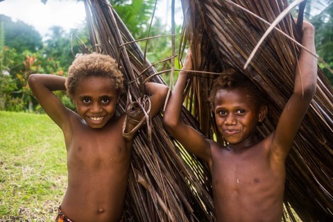 Two young boys carrying palm leaves