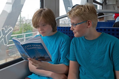 Young people on a language trip read an English travel guide on the train