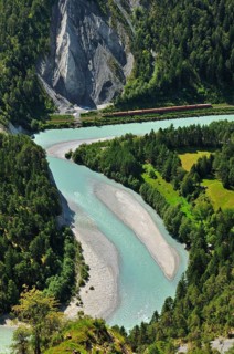 Train of the Rhaetian Railway on the riverbanks of the Vorderrhein