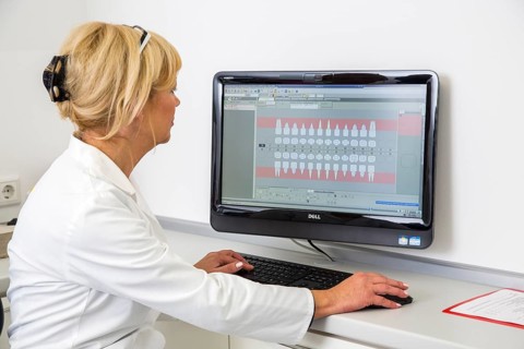 Dental assistant entering a patient's data into the electronic medical record