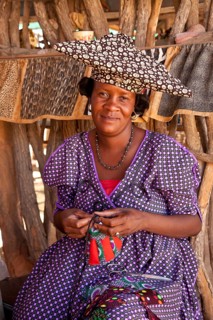 Herero woman with typical headdress sewing souvenirs