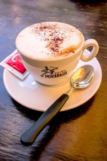 Cappuccino with a sugar sachet and a spoon