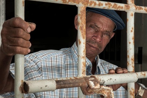 A former prisoner standing behind a door with iron bars