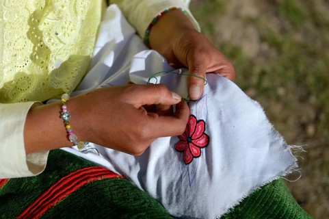 Young woman embroidering a cloth with traditional patterns