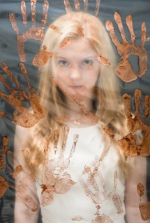 Young woman behind plastic sheet covered with handprints