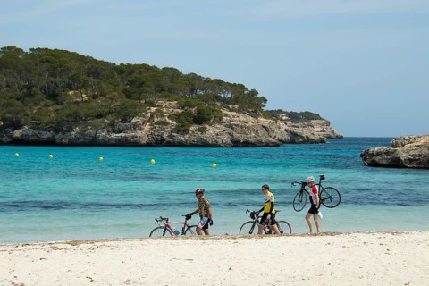 Racing cyclists walking along the beach