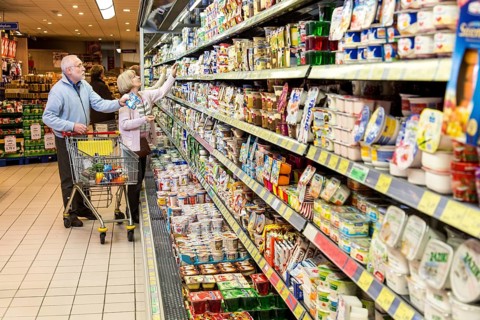 Senior couple shopping with a shopping trolley in the refrigerated dairy section in a supermarket