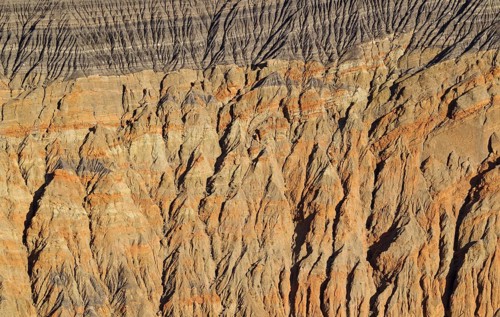 Exposed fissured bedrock of orange-colored conglomerate on the crater wall of Ubehebe Crater