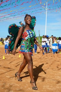 Teenage girl presenting a butterfly costume made of recycled materials such as lids of plastic bottles at a fashion show of a social project