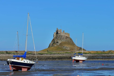Sailing boats at low tide in the bay off Lindisfarne Castle