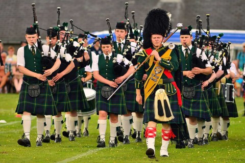 Pipe major leading a pipe band on the sports ground at the Highland Games
