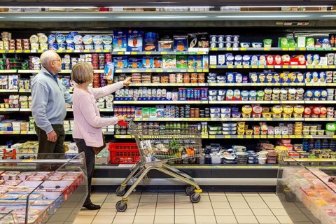 Senior couple shopping with a shopping trolley in the refrigerated dairy section in a supermarket