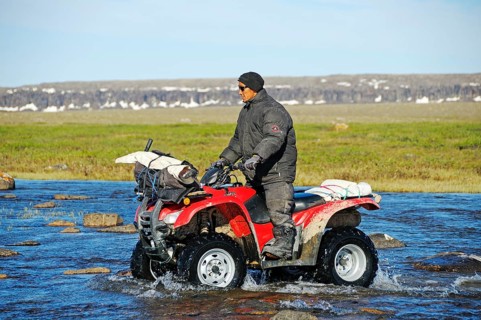 Man of the Inuit people riding a quad bike