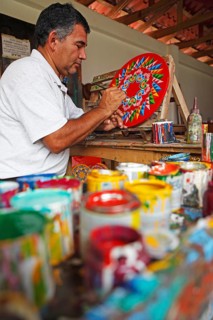 Man painting the hub of a traditional oxcart or Carreta