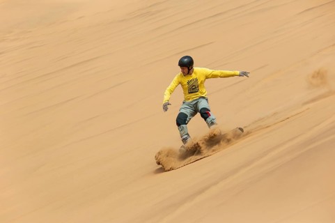 Sand boarding in the dunes of the Namib Desert