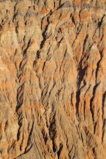 Exposed fissured bedrock of orange-colored conglomerate on the crater wall of Ubehebe Crater