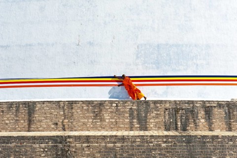 Monk tying a cloth around a large white stupa