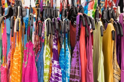 Women's cotton dresses for sale on a clothes rack at an outdoor market