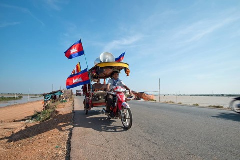 Cambodian monks and novices on a tuktuk with Buddhist flags and national flags of Cambodia at a protest