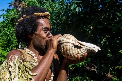 Man blowing in a giant shell