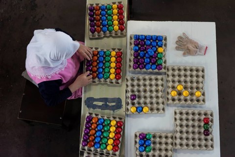 Worker during quality control of colourful dyed Easter eggs
