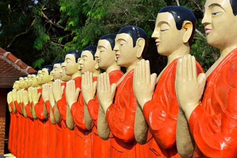 Figures of Buddhist monks in front of a monastery