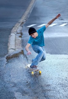 Teenager riding a longboard downhill on a wet street
