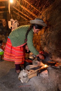 Young woman cooking on an open fire in her traditional kitchen