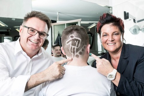 The two hairdressers Gerhard Ostler and Sylvia Ostler posing with a customer who has received a Football World Cup hair tattoo from them