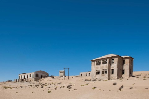 Houses of a former diamond miners settlement that is slowly covered by the sand of the Namib Desert