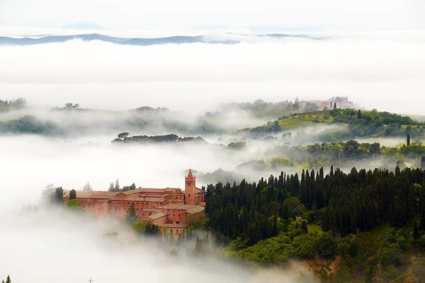 Monte Oliveto Maggiore abbey with mist-shrouded valleys