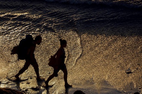 Two backpackers walking along the beach