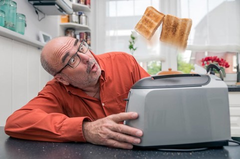 Man watching 2 slices of toast being ejected from a toaster