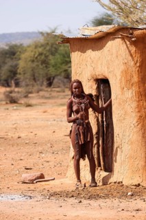 Young Himba in front of her hut