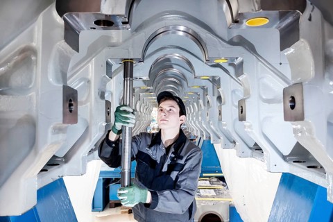 Employee fitting a tension rod into the engine frame of a marine engine