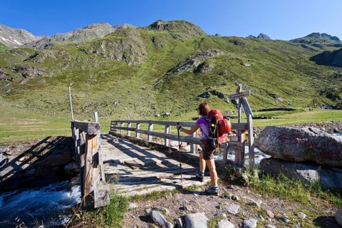 Female mountain climber at Timmelsalm alpine pasture crossing Timmlserbach stream