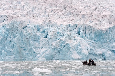 Tourists in a rubber dinghy in front of the rim of the Monacobreen Glacier