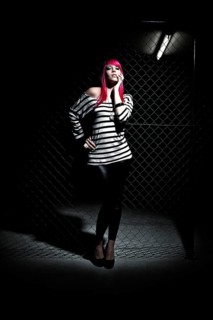 Woman with pink hair in front of a chain link fence