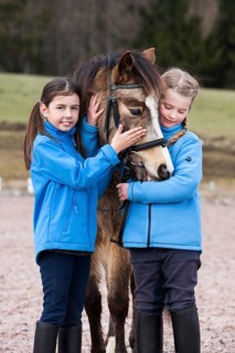 Two girls standing beside a pony
