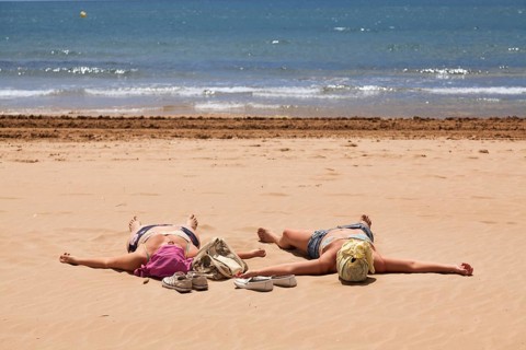 Two women with covered heads sunbathing on the beach