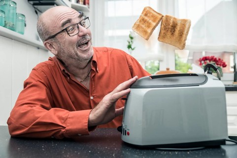 Man watching 2 slices of toast being ejected from a toaster