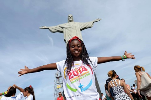 Young woman from Mozambique with her arms outstretched in front of the Christ the Redeemer statue