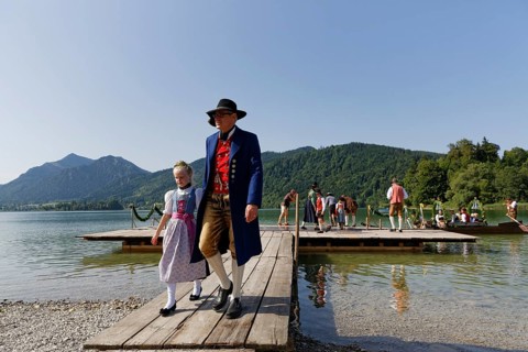 Locals wearing traditional costumes disembarking a boat at a jetty