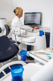 Dental assistant entering a patient's data into the electronic medical record