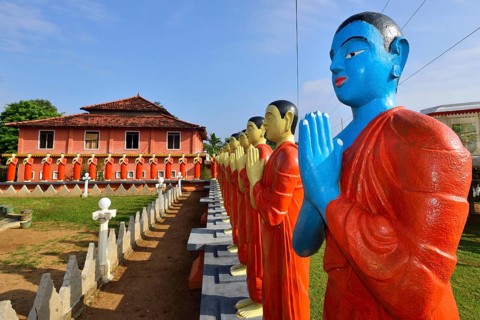 Figures of Buddhist monks in front of a monastery