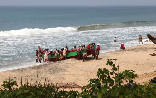 Fishermen pushing their boat out of the water onto the beach