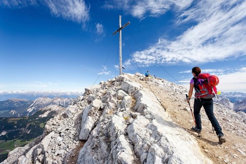 Mountaineer at the summit cross of Mt Heiligkreuzkofel of the Fanes Group in the Fanes-Sennes-Prags Nature Park