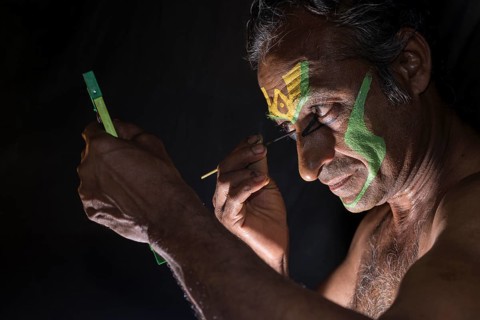 A Katakali artist is applying the make up of the character Arjun for the Kiritam play during a temple festival