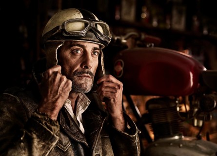 Man with old leather jacket putting on an old motorcycle helmet